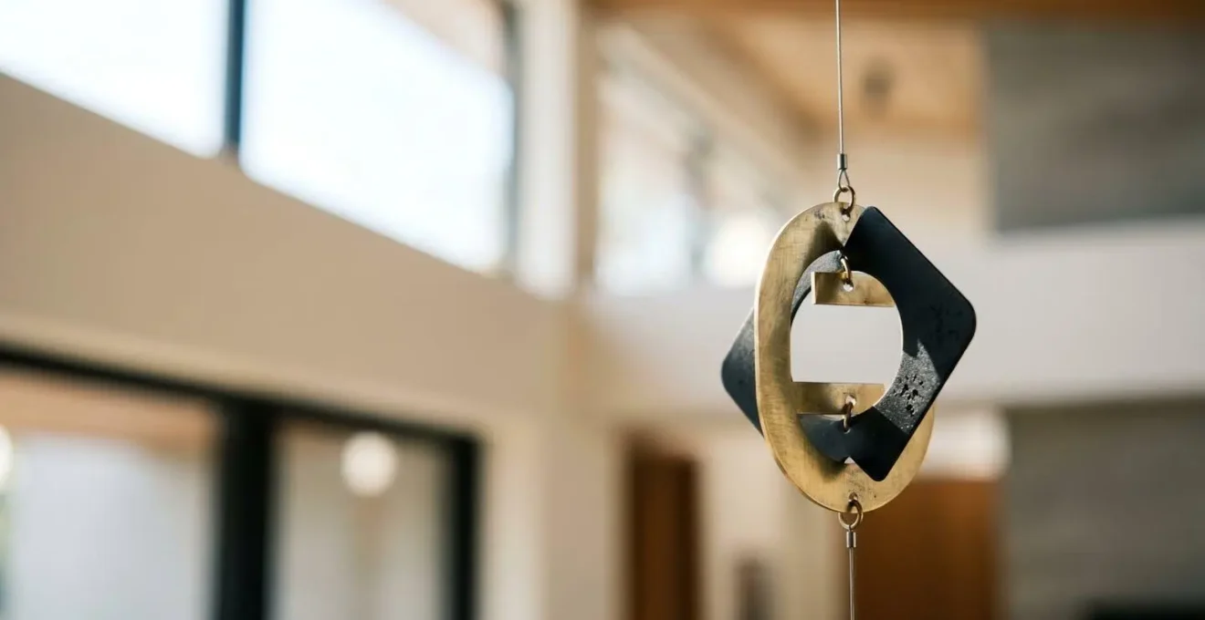Elegant kinetic mobile sculpture suspended in architectural space with subtle air currents creating gentle motion